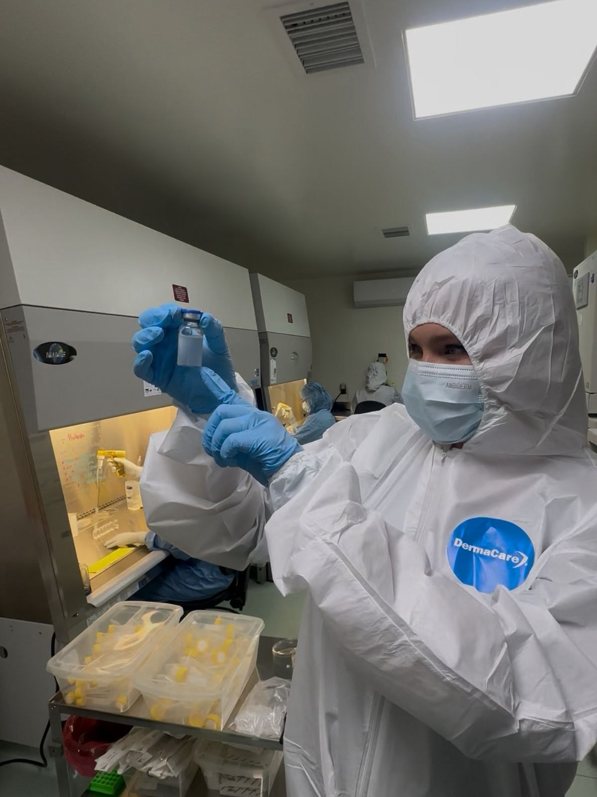 A technician inspects a vial in the cleanroom